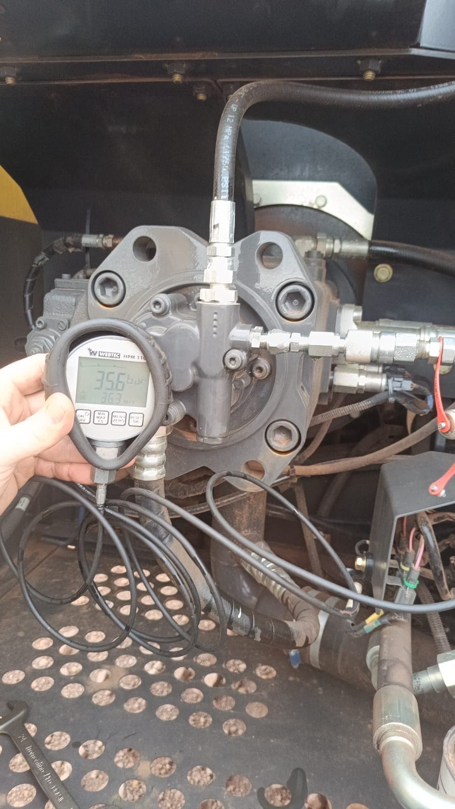 Medição de pressão com manômetro digital em bomba hidráulica da máquina